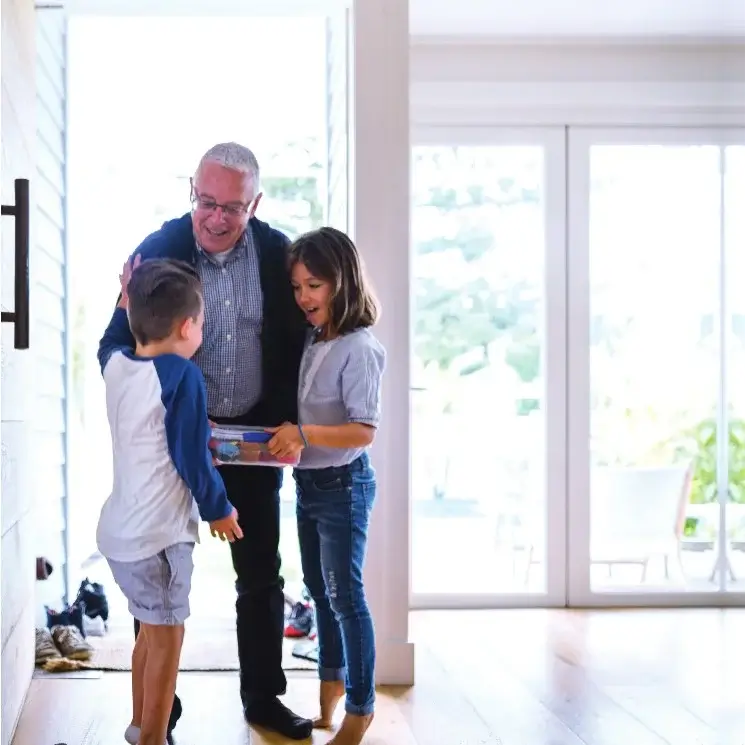 Un grand-père souriant entouré de ses petits-enfants dans une maison sécurisée par Alarme Presqu'ile Sécurité. Installation d'un système alarme